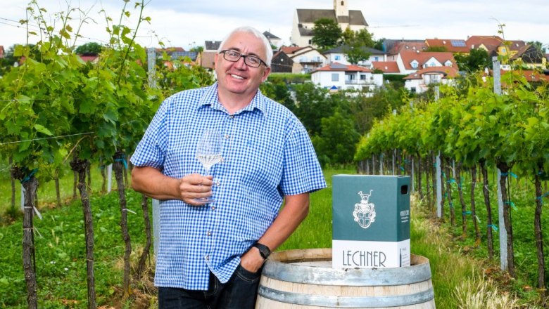Reinhard Lechner, © zaiser@extra.krems.at Man in a plaid shirt with a wine glass in a vineyard, in the background a village with a church.