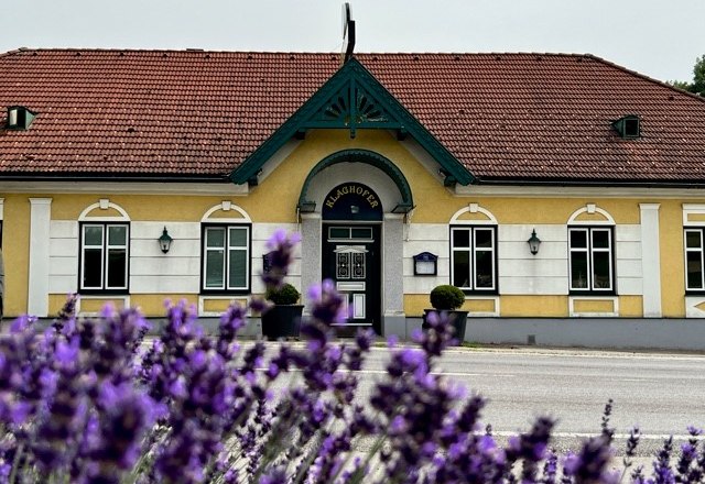 TDR_Gasthaus Klaghofer, © Klaghofer A yellow building with a red roof and green decorations, lavender in bloom in the foreground.