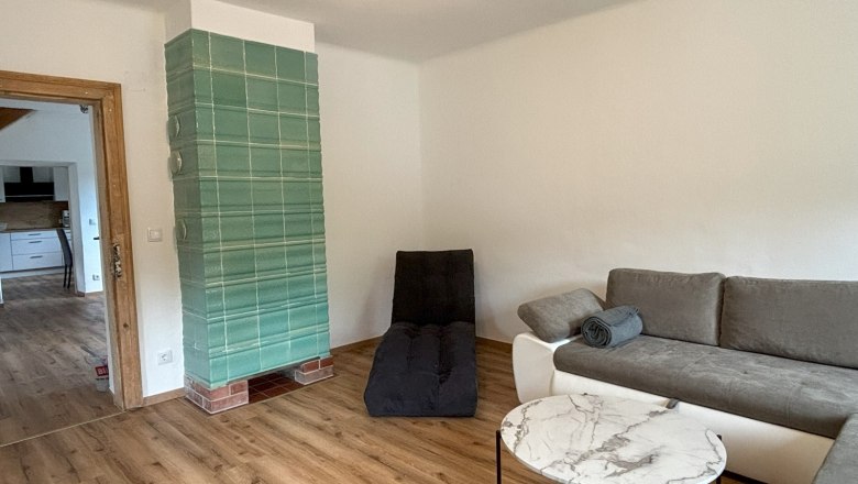 Living room, © Michael Hofer Living room with gray sofa, round marble table and green tiled stove.