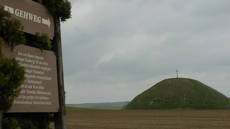 Leeberg, © Gemeinde Großmugl A hill with a cross on top, next to it a sign with the inscription 'Gehweg' (footpath).