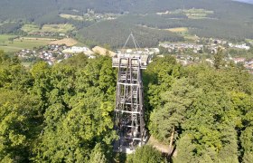 Gfiederwarte, © Stadtgemeinde Ternitz Observation tower surrounded by trees with a view of a village and wooded hills in the background.