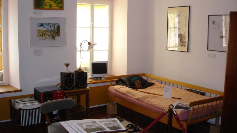Gottfried von Einem Museum, © Stadtgemeinde Maissau Interior view of a museum room with a bed, pictures on the wall and a small desk with a computer.