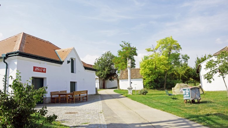 Maulavern wine cellar lane, © Weingut Arthold Wine cellar lane with white building and benches in front of a winery on a sunny day.