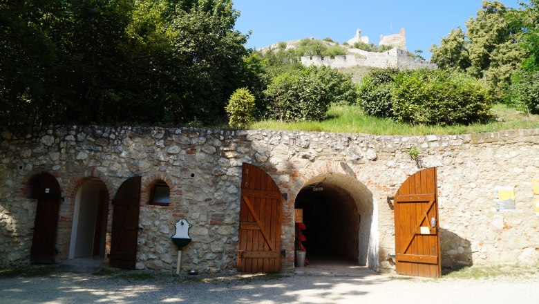 Castle cellar, © Marktgemeinde Staatz Entrance to a castle cellar with wooden doors, above a ruined castle on a hill.
