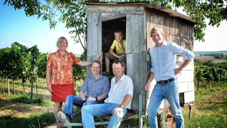 Fleckl family, © Alexander Fleckl A family poses in front of a small wooden wagon in a vineyard.