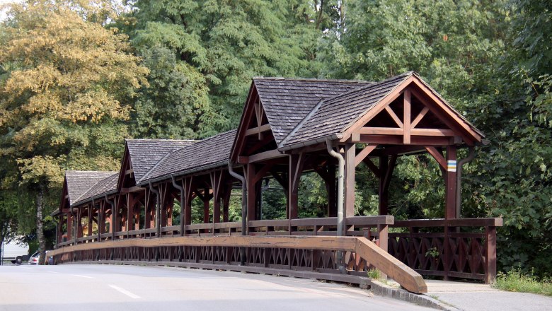 Leithabrücke Katzelsdorf, © Steindy, CC BY-SA 3.0 Wooden bridge with covered walkway in a green setting.