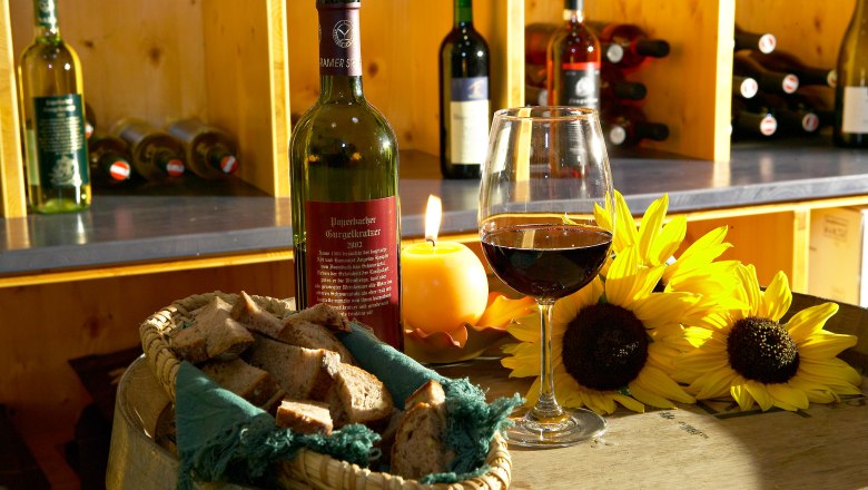 Vinoduct, © Vinodukt, Foto: Franz Zwickl Wine bottle and glass on a barrel with bread and sunflowers.