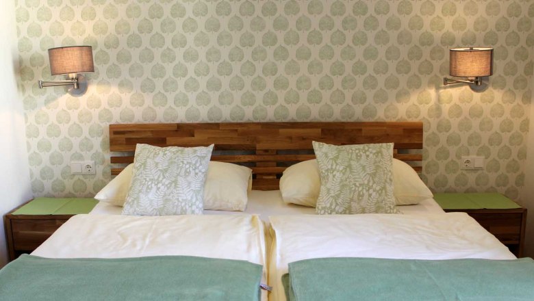 Cozy rooms, © Magdalena Donhauser Cozy room with double bed, patterned wallpaper, wall lamps, bedside tables and pillows.