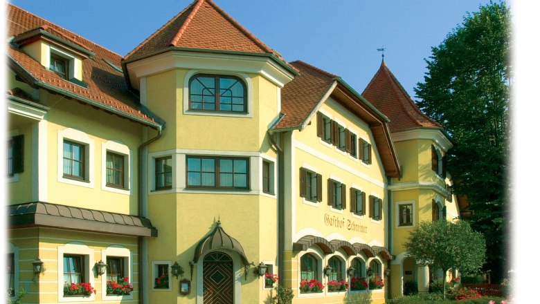 Schreiners - the Waldviertel House, © Schreiners – das Waldviertel Haus Yellow building with red roofs and many windows, surrounded by trees.