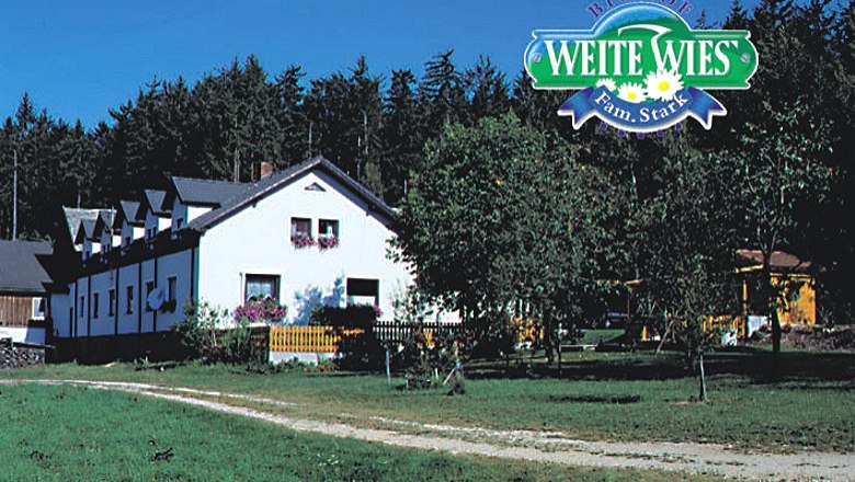 Stark organic farm, © Biohof Stark A white farmhouse with flowers in front of a forest, above it the logo 'Biohof Weite Wies Fam.