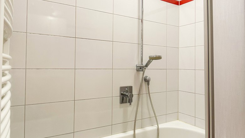 House Morgensonne Bathroom, © Fam. Pauker Bathroom with bathtub, shower head and red tiles.