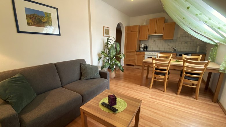 Vacation apartment Traube, © Trachsler Living room with gray sofa, wooden table, dining table and kitchen in the background.