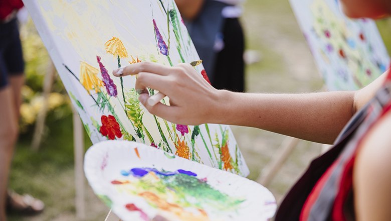 Art Adventure, © Art Adventure Person paints with finger paints on a canvas outdoors.