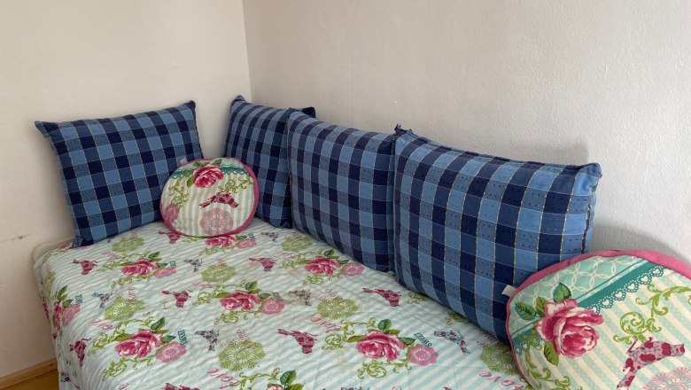 Children's room with pull-out bed, © Wiener Alpen A children's room with a pull-out bed decorated with a flowered blanket and blue cushions.