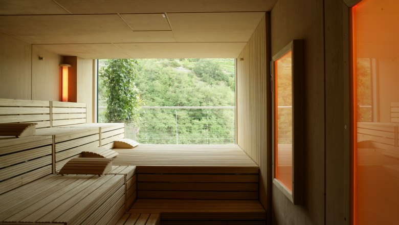 Sauna, © Steigenberger Hotel and Spa Interior view of a modern sauna with wooden benches and a large window with a view of the green landscape.