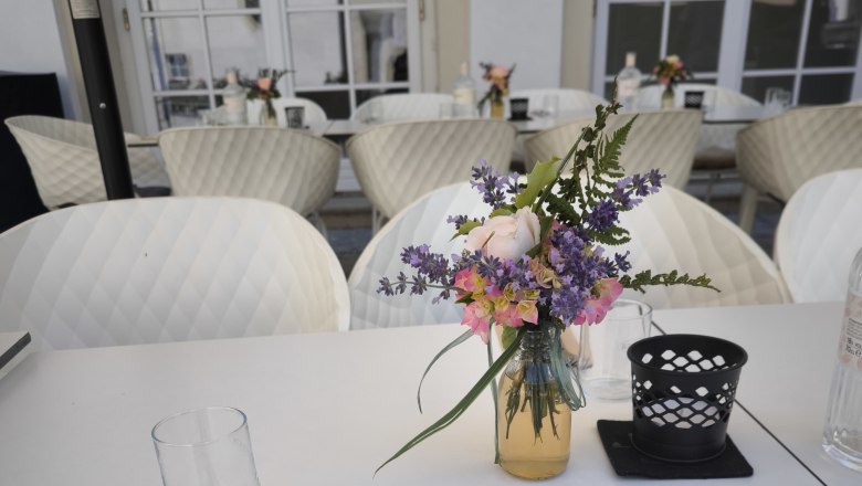 Terrace at the Freiherr, © Markus Jokesz Set table on a terrace with a bouquet of flowers and cutlery.