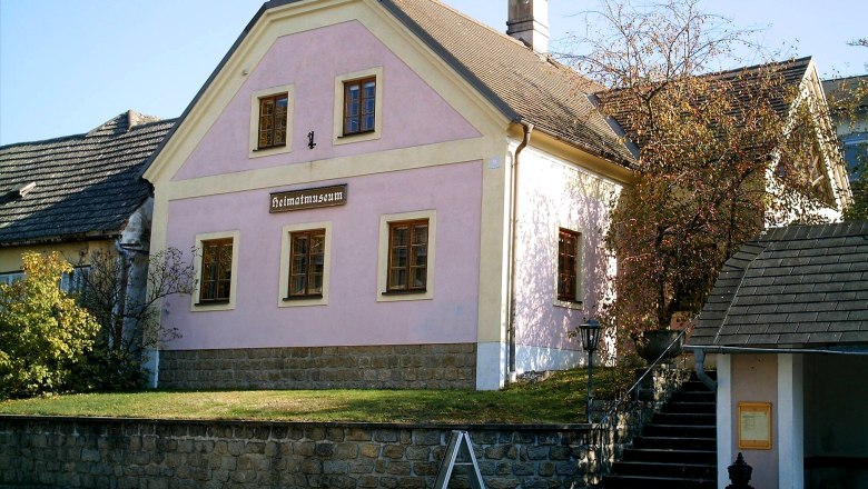 Museum of local history Kautzen, © Heimatmuseum Kautzen A pink building with the inscription 'Heimatmuseum' in Kautzen, surrounded by trees and a cobbled path.