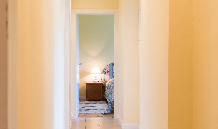 Main picture, © Mag. Harald Grassel A bright hallway leads to a bedroom with bedside lamp.