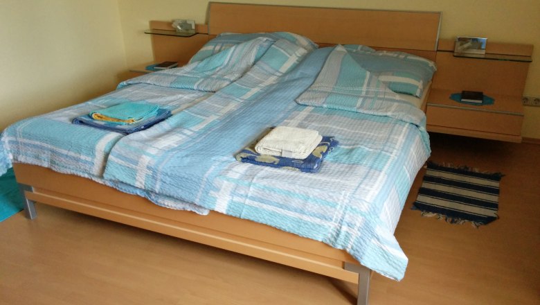 Double bed in the beech room, © Reep Double bed with blue bed linen in a room with wooden floor.