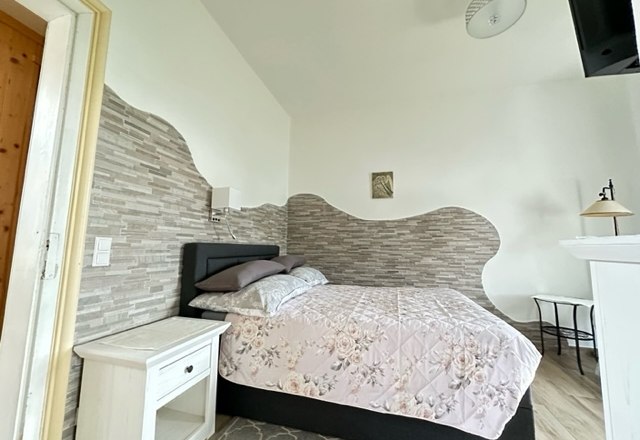 Room single bed, © Schloss Gut Ziegersberg A cozy bedroom with a single bed, floral comforter cover, bedside table and decorative wall design.