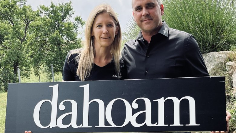 The hosts at "dahoam", © Anita Gradwohl, dahoam Two people are holding a sign with the inscription 'dahoam' outside.