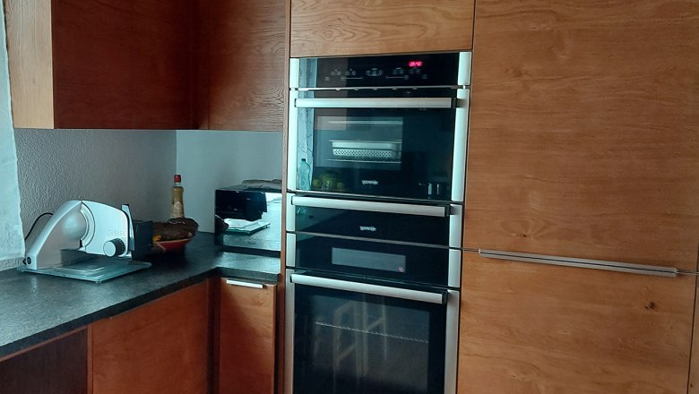 Kitchen, © Bernadette Gierlinger Modern kitchen with wooden cupboards, built-in oven and worktop with kitchen appliances.