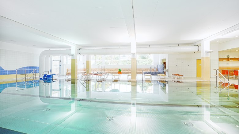 Zwentendorf indoor swimming pool, © Florian Schulte Interior view of a bright indoor pool with swimming pool, sun loungers and large windows.