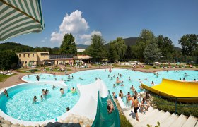 Gloggnitz natural swimming pool, © Wiener Alpen, Foto: Franz Zwickl An outdoor pool with several pools, water slides and lots of people on a sunny day.