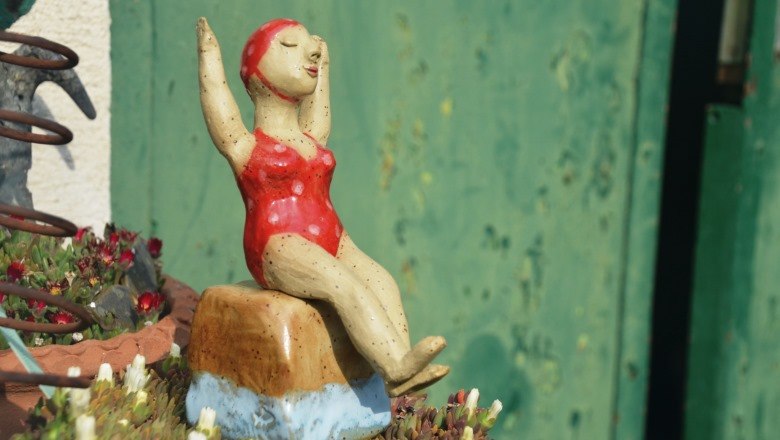 badenixe_klein_c_family-mahr, © Familie Mahr Ceramic figure of a woman in a red swimsuit sitting on a rock.