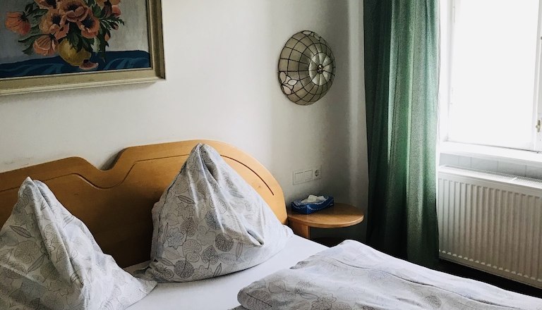Room example, © Fam. Probst A cozy bedroom with a double bed, green curtains and a flower picture on the wall.