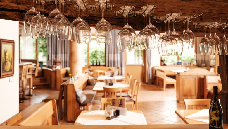 Wine.restaurant Neustifter, © Weinviertel Tourismus / Michael Reidinger Interior view of a restaurant with hanging wine glasses and wooden furniture.