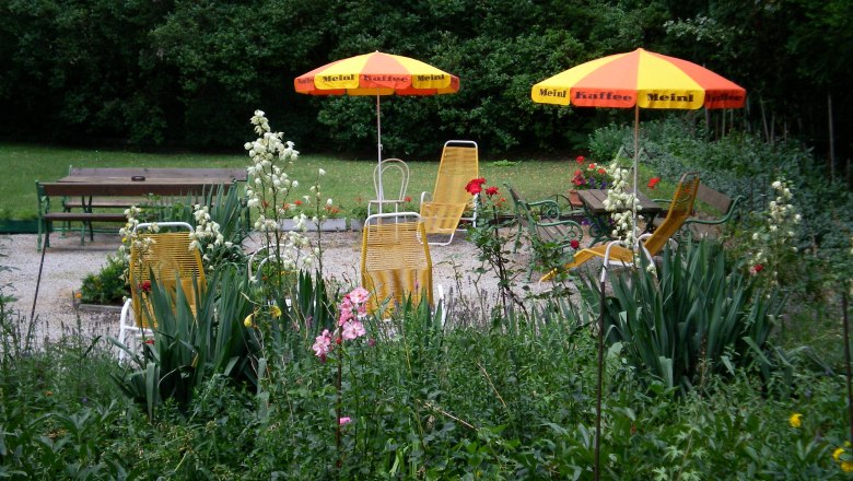 Garden, © Zauza Garden with yellow sun loungers and parasols, surrounded by flowers and trees.