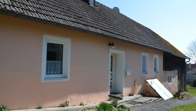 vacation home-2_2, © Karl Temper A simple, single-storey house with a pink façade and gray roof. Plants and decorations can be seen in front of the house.