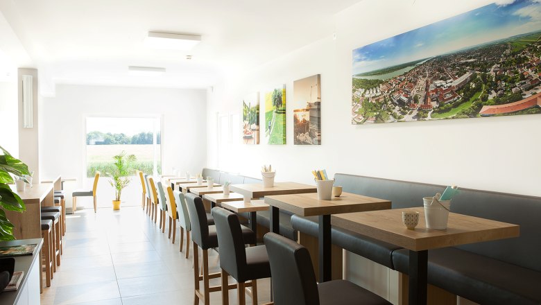 Breakfast room, © Hotel Tullnerfeld Breakfast room with gray upholstered seating and wooden tables.