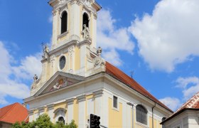 Augustinian Church, © Stadtgemeinde-Korneuburg Baroque church with tower and clock against a blue sky.