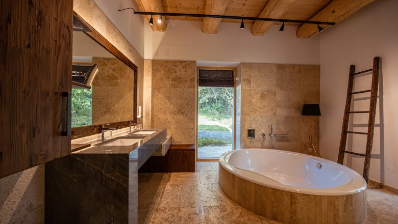 Vacation home by the lake, © Niederösterreich Werbung / Maximilian Pawlikowsky Modern bathroom with free-standing bathtub, large mirror and wooden beamed ceiling.
