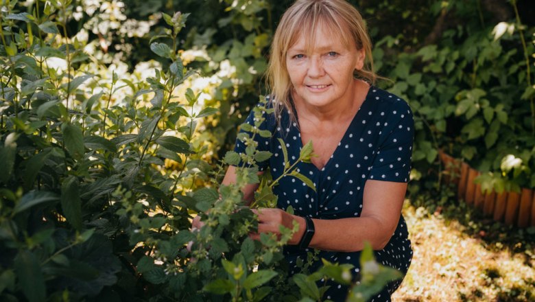 Landlady Gabriele Hader, © Niederösterreich Werbung/Daniela Führer A woman in a polka-dot dress kneels in a garden and looks at plants.