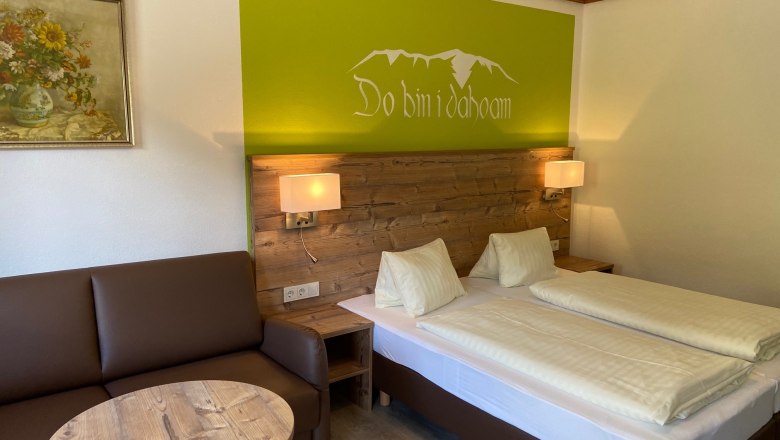 Double room, © Wiener Alpen Cozy double room with wooden furniture, sofa, table and wall decoration.
