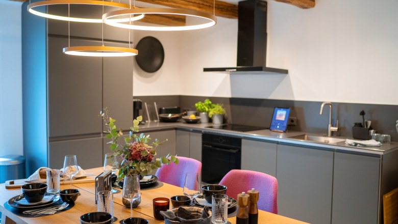 Chalets & places full of WONDER - Weidehaus De Luxe, © WUNDERVOLL eben Modern kitchen with dining table set for four and stylish lighting.