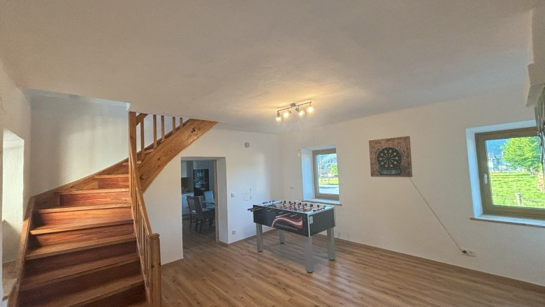 Common room with Wuzzler and dartboard, © Wiener Alpen A common room with table football table, dartboard on the wall, wooden staircase and two windows.