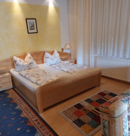 Guest room Weixelbaum, © Familie Weixelbaum Comfortable guest room with double bed, colorful carpets and wooden furniture.