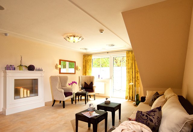 Wellness relaxation area, © Residenz Wachau A cozy wellness relaxation area with fireplace, armchairs, sofa and small table, decorated with candles and plants.