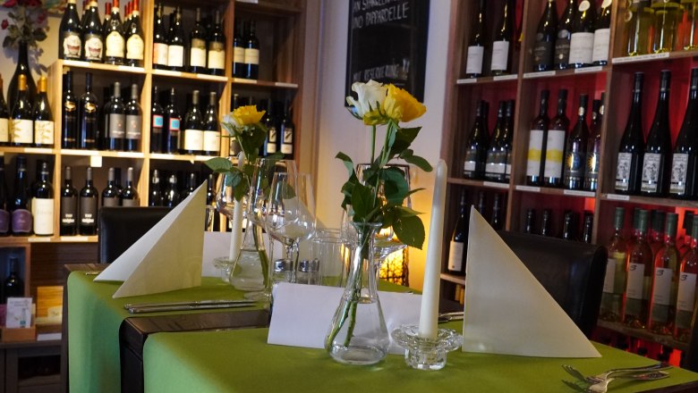 Café Leopold Schwechat, © Café Leopold A stylishly laid table in a café with a green tablecloth, yellow roses and bottles of wine in the background.