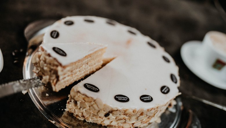 Homemade cakes, © Nicole Seiser A cut cake with almonds and chocolate decoration on a tray.