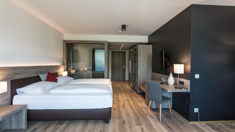 Spacious room in the wine lodge, © KASTNER NEW MEDIA - kastner.tv Modern hotel room with double bed, desk and wooden floor.