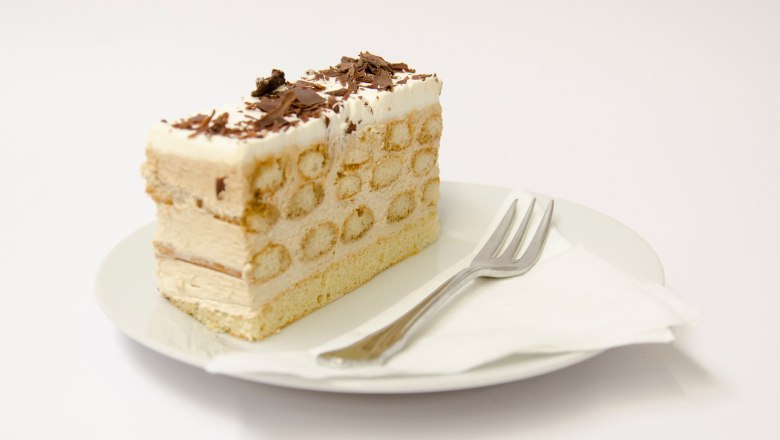 Cafe Lechner Malakofftorte, © Bäckerei Lechner A piece of Malakoff cake on a plate with a fork.