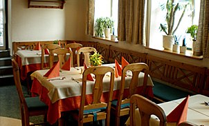 laid table, © Gasthaus Die kleine Post A cozy restaurant with laid tables and wooden chairs.