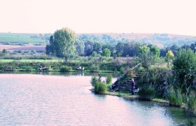 Quiet fishing pond near Unterretzbach, © Gemeinde Retzbach A quiet fishing pond with anglers, surrounded by green countryside and vineyards in the background.