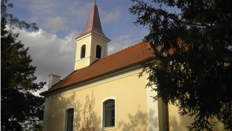 Floriani Chapel Oberrohrbach, © Gemeinde Leobendorf Floriani Chapel Oberrohrbach with tower and mural, surrounded by trees.