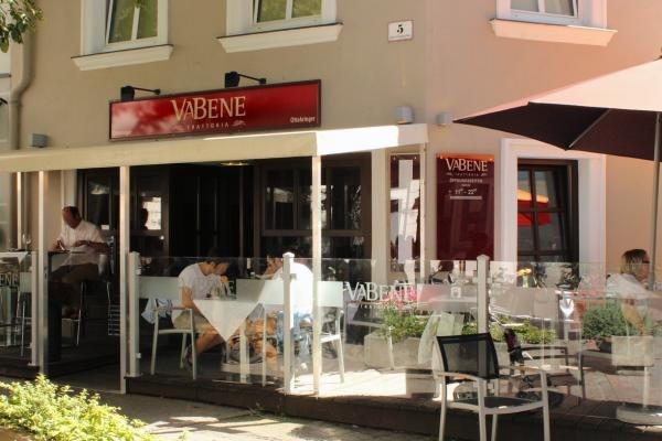 Va Bene pub garden, © Koran Exterior view of a café called Va Bene with sidewalk seating and guests at tables.